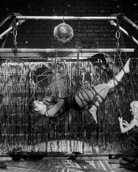 A rope suspension inside a frame hung with silver tinsel and a mirror ball.